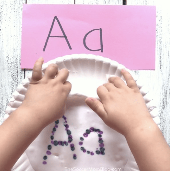 phonemic awareness shows a child playing with slime with the letter Aa on it.