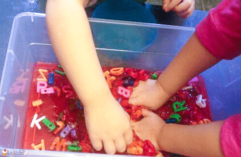 phonemic awareness shows children playing in a bucket with jello and alphabet letters.