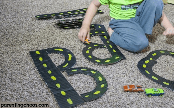 letter games shows a child playing with diy road tracks that make letters.