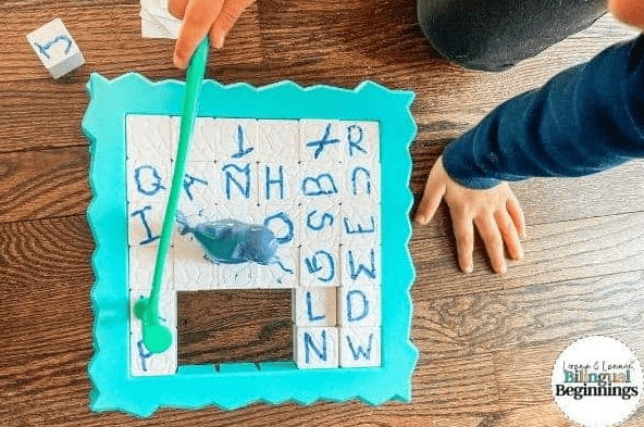 phonemic awareness shows a child hitting game pieces with the alphabet on them out of the game board