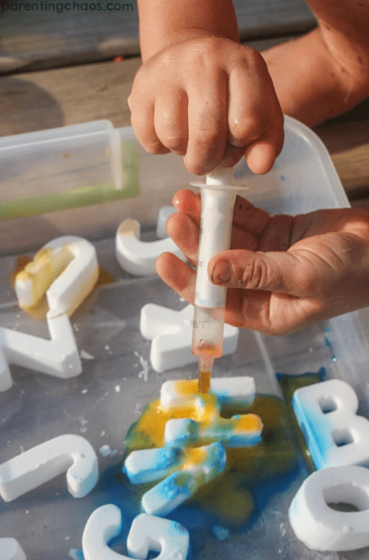 phonemic awareness  shows a child squeezing a liquid onto fizzing alphabet letters.