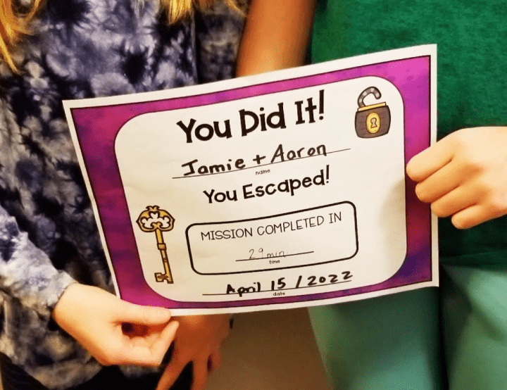 diy escape room shows two children holding a certificate
