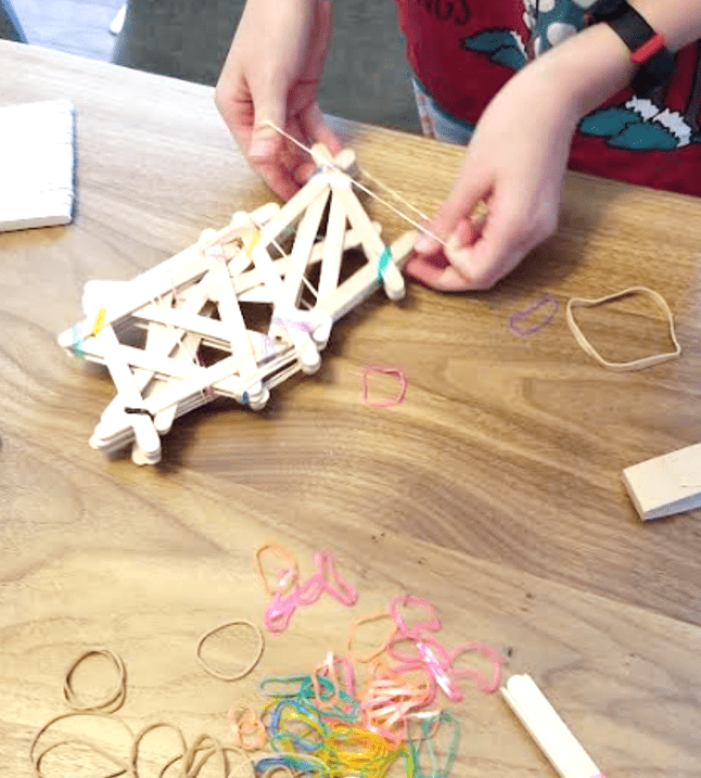 stem challenges shows a child building with popsicle sticks and elastics