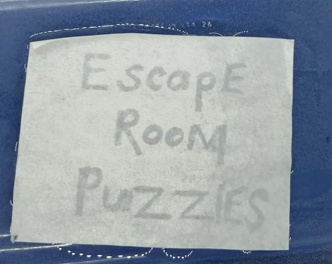 hands on puzzles shows a piece of paper in water with the words escape room puzzles.