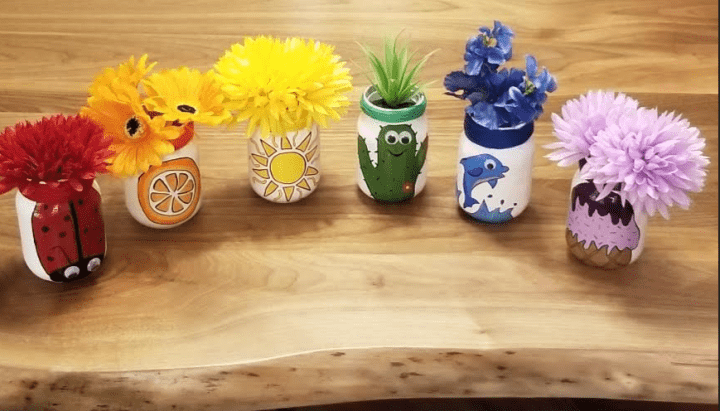 mason jar crafts shows six rainbow jars with flowers in each