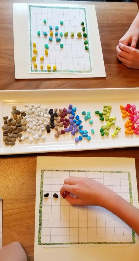 nature art shows two children putting colored stones onto a hundreds graph.