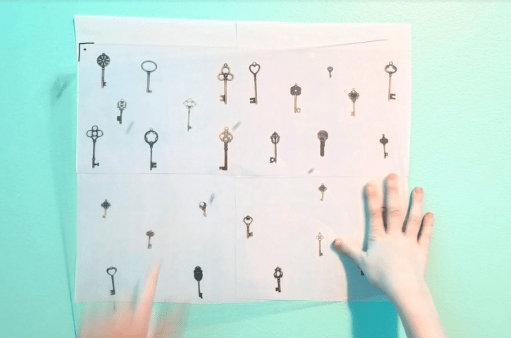 escape game shows a child holding a clear board on top of pictures of keys on the wall.