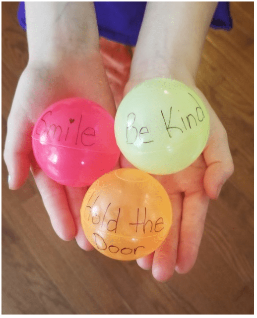 family games with kindness shows a child holding three balls with kind words on them.