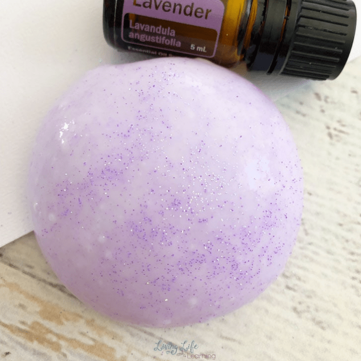 sensory play shows a ball of purple slime and lavender essential oil bottle