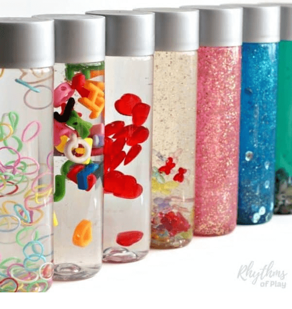 sensory bottles shows seven bottles with different small items in each