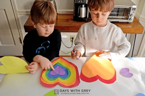 valentines day craft shows two children making a heart craft.