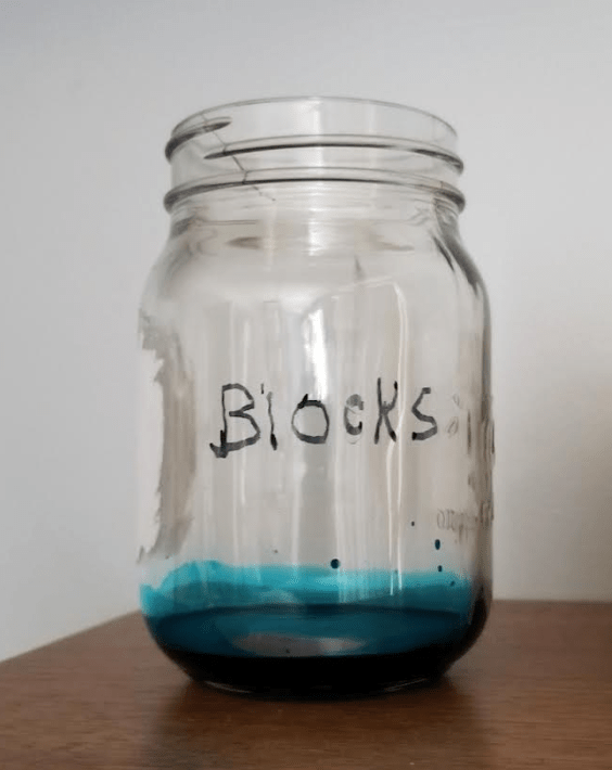 escape room ideas shows a clear jar with the word blocks written on it and dark liquid in the bottom