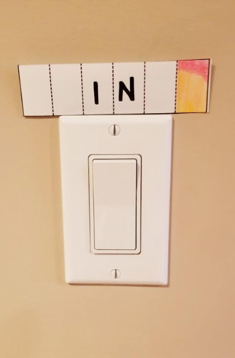 escape room shows a piece of paper with 'in' written on it near a light switch