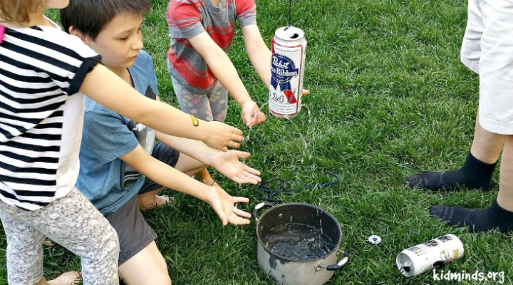 summer STEM activity shows children around a can with holes in it spraying water.