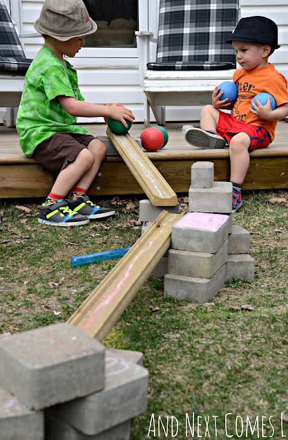 summer STEM activity shows two children rolling large balls down a ramp