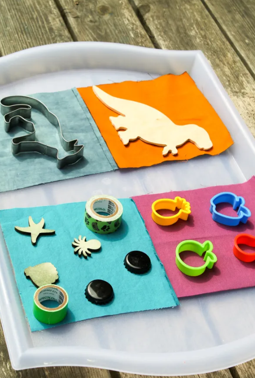 summer stem activity shows a bunch of objects set on a tray and on fabric