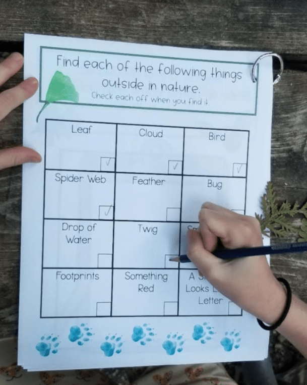 outdoor education booklet shows a child putting checkmarks on a nature hunt chart.