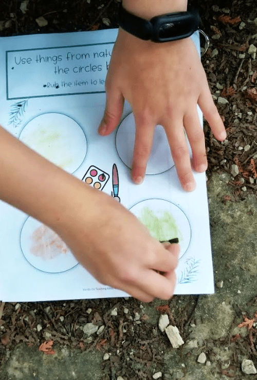 outdoor education shows a child rubbing a leaf on a circle in a booklet.