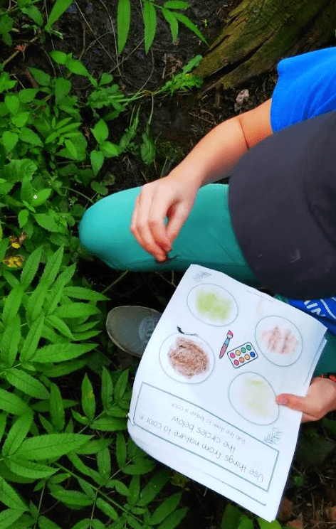 outdoor learning activities shows a child in nature with mud in hand and a nature booklet.
