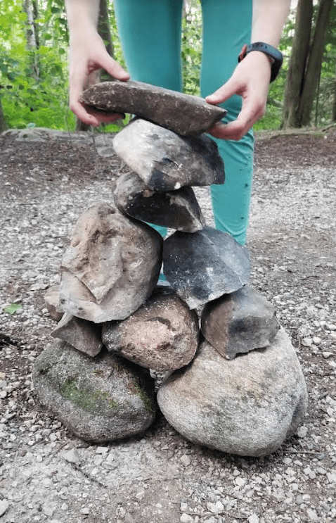 outdoor education shows a child stacking huge rocks.