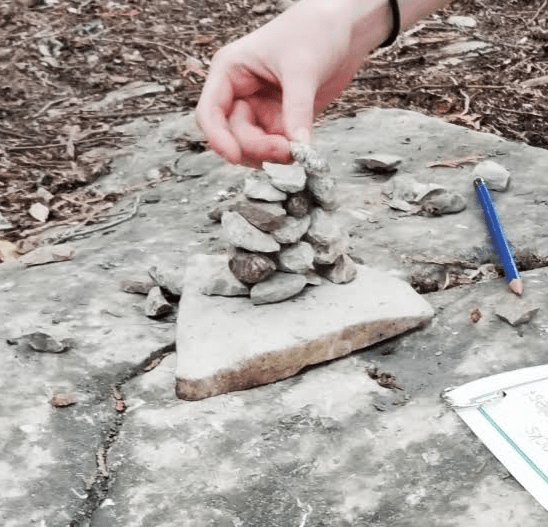 outdoor education shows a child stacking rocks.