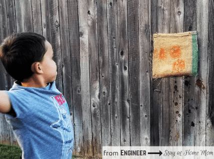 fall stem activities shows a child throwing a paintball onto a fabric attached to the fence.