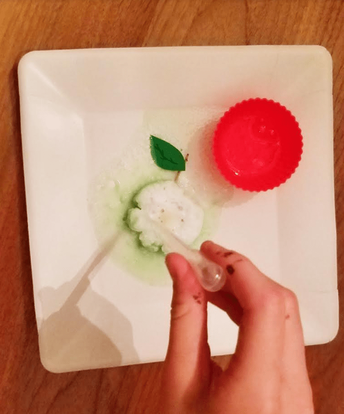 STEM for kids shows a child using an eye dropper onto a green baking soda puck and it fizzing.