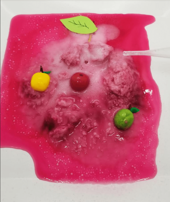 fizzing apple science experiment shows a pile of fizzed baking soda with apple figures inside.