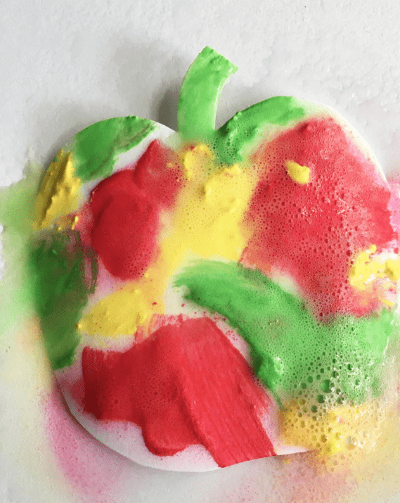 fall stem activity shows a piece of paper cut into an apple shape with blotches of fizzing colors. 