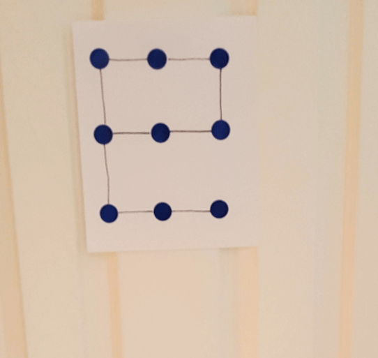 escape game shows the letter E made with dots on a sheet on a door.