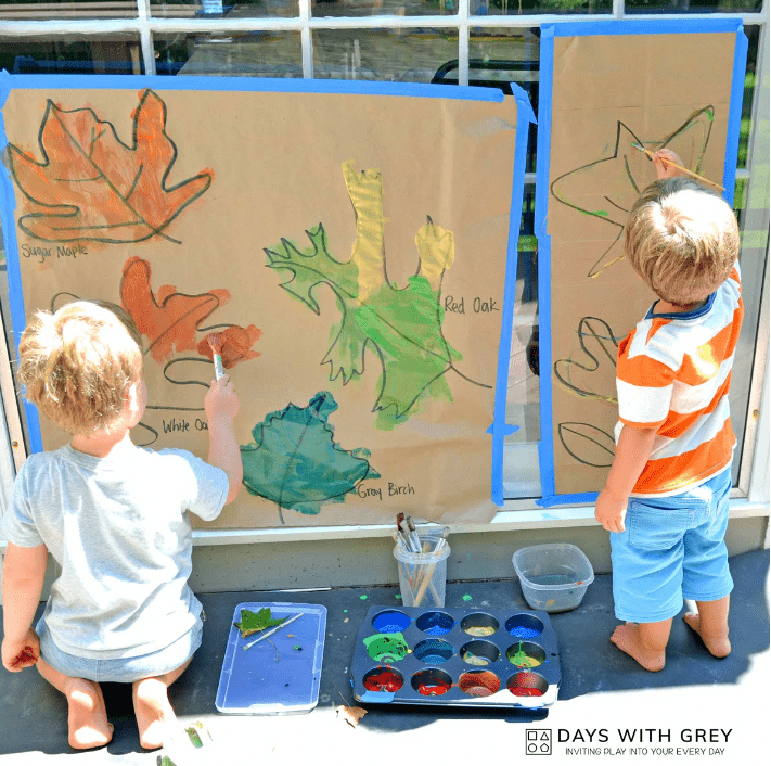 fall outdoor learning activities shows two children painting leaf outlines.