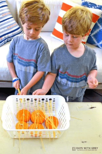 STEM activity shows two children playing with pasta in a container with pumpkins in them.