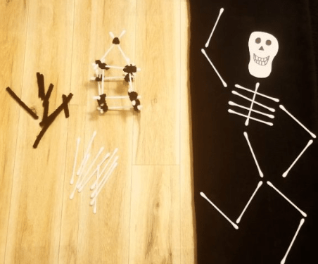 Halloween STEM shows a skeleton made from cotton swabs and a mini skeleton house.