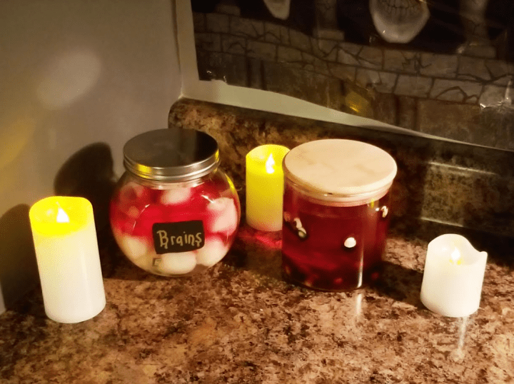 diy escape room shows containers with what is meant to look like brains and yucky halloween stuff and candles.
