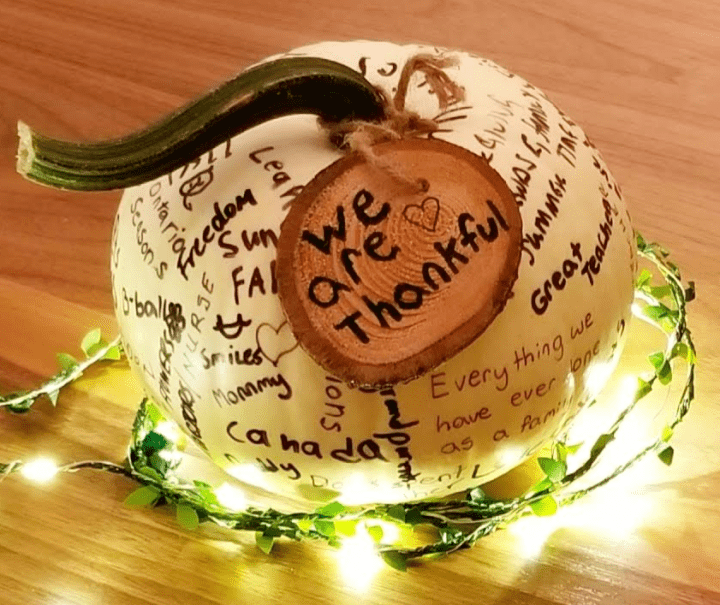 Thanksgiving activity for families shows a white pumpkin with words printed all over it.