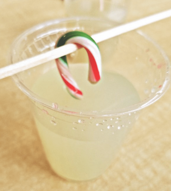 STEM for kids shows a candy cane on a stick being held above a cup of water.