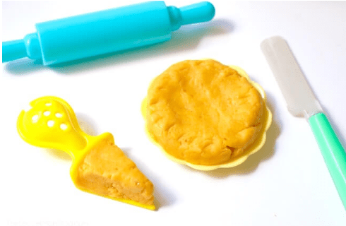 sensory activity shows orange pumpkin slime in a bowl and on a plate and then a rolling pin and plastic knife.