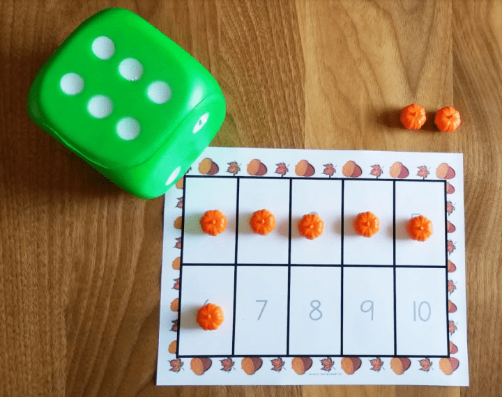 fall worksheets shows a ten frame with six pumpkin pieces in it and a large green dice.