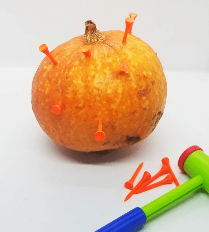 fall centers for kindergarten shows a pumpkin with golf tees hammered into it.