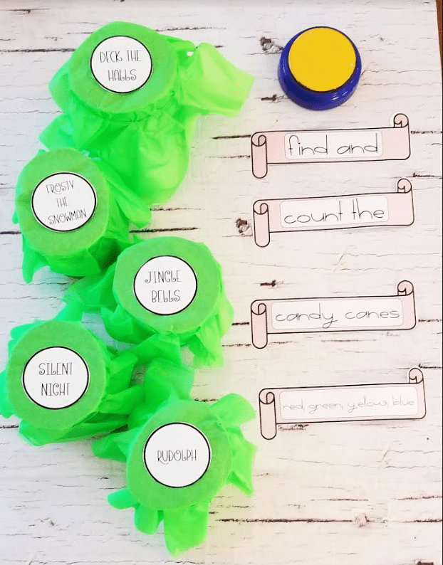 DIY Christmas Escape Room shows five cylinders with Christmas carol names and puzzle strips and  a button.