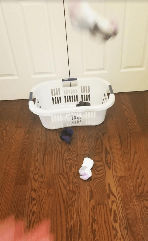 family active games shows a person throwing a sock into a laundry basket.