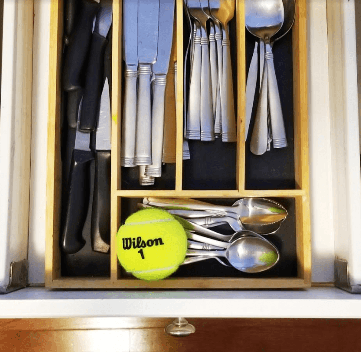 family games shows a cutlery drawer with a tennis ball in it.