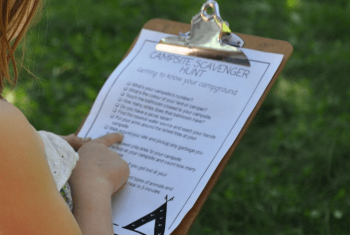 camping scavenger hunt shows a child pointing to words on a list.