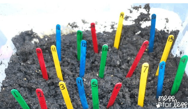 number hunt shows numbered colorful popsicle sticks in dirt.