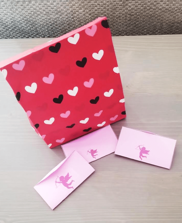 diy valentines escape room shows a heart bag with a few valentines in front of it.