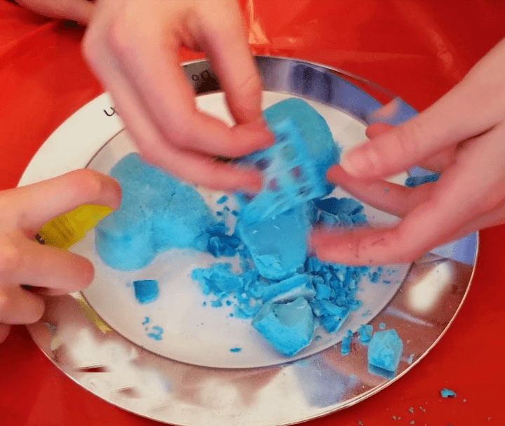 escape room for kids shows children breaking apart a blue heart mold.