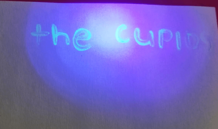 valentines escape room show the words the cupids glowing on the paper.
