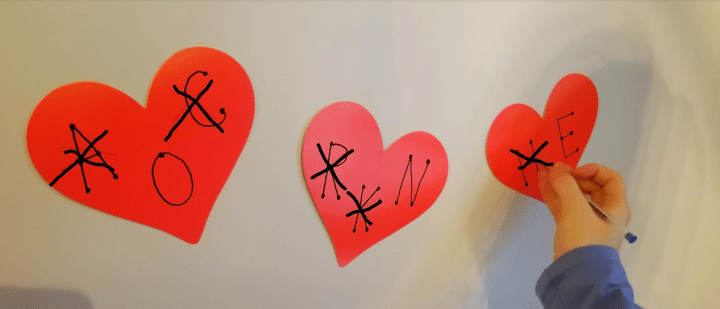 valentines escape room shows a child crossing out letters on red hearts on the wall.