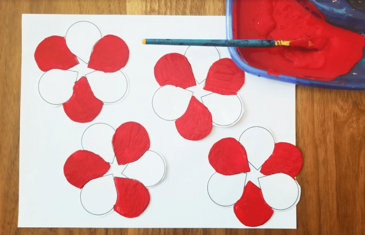 valentines day for kids shows four hearts with some red petals painted.