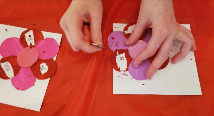 diy escape room shows a child holding a coin and scratching paint off of a painted flower.